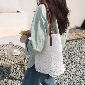 Detail of white hollow floral lace tote bag with reinforced brown leather shoulder strap
