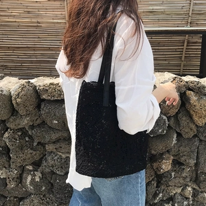 Detail of black lace tote bag featuring delicate floral patterns and leather shoulder strap