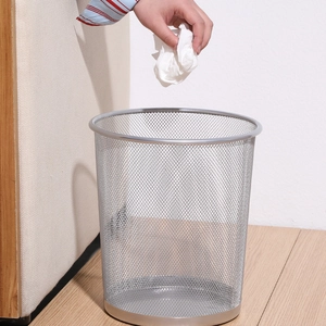 Silver round metal mesh waste basket shown in use on a modern wooden floor setting