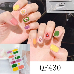 Détail macro de stickers ongles arc-en-ciel avec motifs floraux et couleurs unies