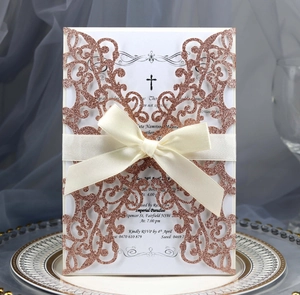 Detail of rose gold glitter laser cut wedding invitation with elegant beige ribbon bow