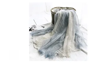 Detail of blue and white linen scarf with raw edges draped on a woven basket