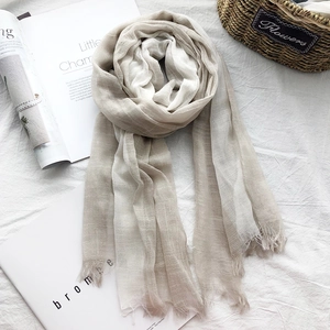 Detail of light beige cotton linen scarf featuring frayed edges and natural texture
