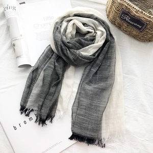 Detail of light cotton linen scarf in grey white gradient with fringe edges on fabric