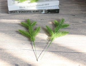 Detail of two artificial green pine needles on a wooden table with a vintage book