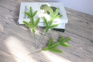 Detailed view of three green artificial pine needles on a rustic wooden table surface