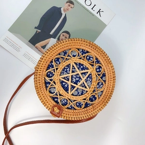 Detail of round rattan crossbody bag featuring floral lining and woven star pattern