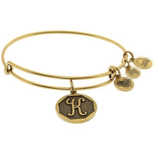 Detailed view of a gold bangle with a hollow circular pendant featuring the letter K engraving