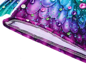 Detailed close-up of mermaid scale print fabric with pearl patterns and double stitching