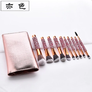 Detail of 10-piece eye shadow brush set with rose gold glitter handles and storage bag