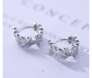 Macro detail of silver leaf branch hoop earrings with elegant laurel design on card