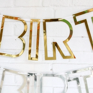Golden and silver Happy Birthday banner bunting with metallic cardstock on white wall