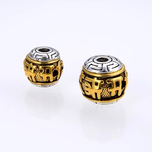 Detailed macro view of 10mm two-tone Tibetan alloy beads with Buddhist mantra relief