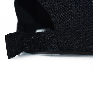 Detail of adjustable Velcro strap on black twill baseball cap with clean stitching