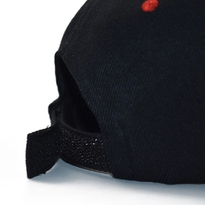 Close-up of black cotton baseball cap back with red accents and adjustable strap