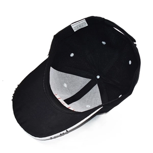 Detailed interior view of black acrylic baseball cap showing red stitching and washing label