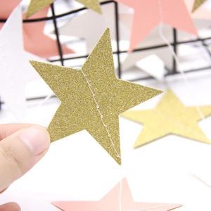 Close-up of glitter gold and pink star garland banners for birthday party decorations