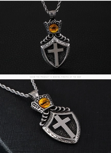 Detailed macro view of vintage stainless steel shield cross pendant with tiger eye stone
