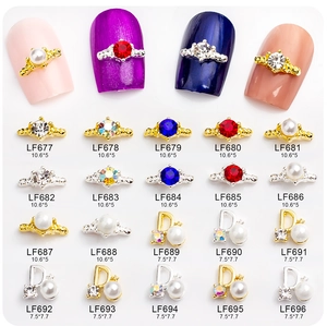 Détail de bijoux d'ongles dorés en forme de couronne et lettre D avec des strass