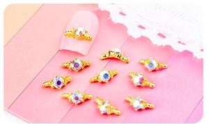 Vue détaillée de bijoux d'ongles en alliage doré avec strass AB sur des ongles roses