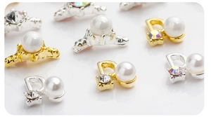 Vue macro de bijoux d'ongles en forme de D et couronne dorés avec perles et strass