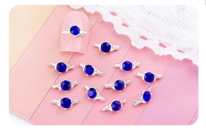 Détail de charmes d'ongles en cristal bleu avec ailes argentées sur ongle