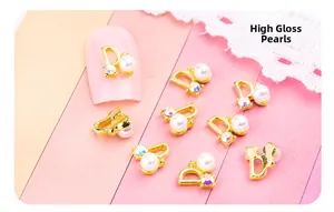 Détail d'un bijou d'ongle doré en forme de D avec perle brillante et cristal étincelant