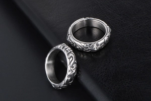 Detail of silver couple rings with engraved stars and swirls on black leather