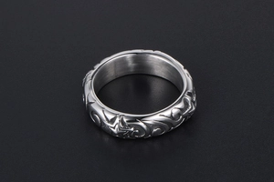 Detailed view of silver metal ring featuring embossed tribal patterns on black background