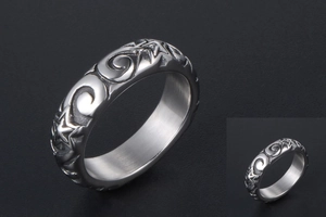 Detail of metal ring featuring vintage star and swirl embossed patterns with glossy finish