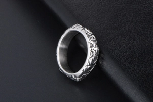 Macro shot of silver metal ring with embossed texture design on black leather surface