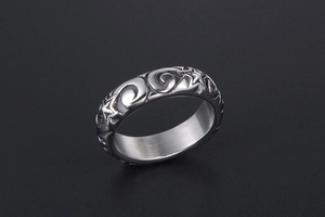 Detailed view of silver ring featuring embossed wave and star patterns with metallic luster