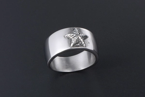 Macro d'une bague large en acier inoxydable argenté avec motif étoile à cinq branches