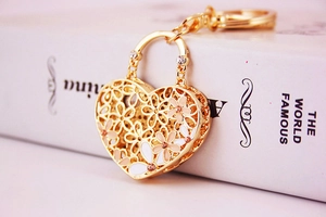 Close-up of golden hollow heart keychain with enamel flowers and sparkling rhinestones