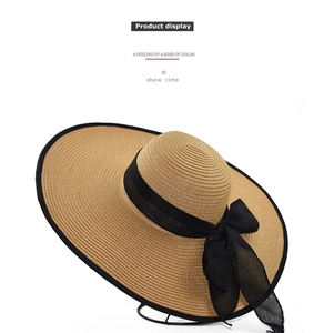 Detailed straw sun hat showing woven texture and oversized black mesh bow decoration