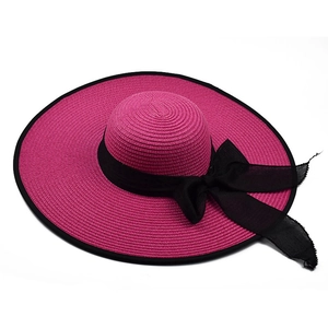 Detail showing the magenta woven straw hat with a wide black ribbon and elegant bow