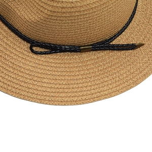 Dettaglio della trama del cappello di paglia intrecciata con nastro nero e fibbia d'oro