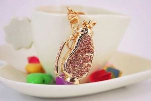 Close-up of a golden golf bag keychain encrusted with sparkling pink rhinestones