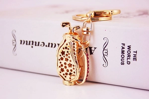 Detail of a gold golf bag keychain with pink rhinestones and a lobster clasp hook