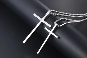 Detailed view of silver titanium steel cross pendants in large and small sizes on ball chain