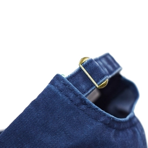 Detail of navy washed cotton baseball cap featuring vintage copper metal buckle adjustment