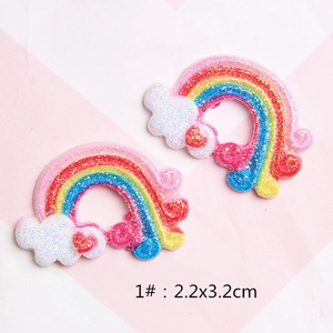 Close-up of rainbow glitter resin charms for DIY hair clips with white clouds and red hearts