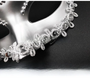 Detailed close-up of a silver masquerade mask featuring sequins and glitter lace textures