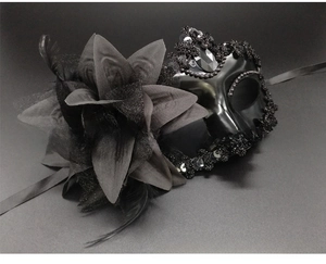 Detail of black masquerade mask with fabric flowers, feathers, and beaded sequins