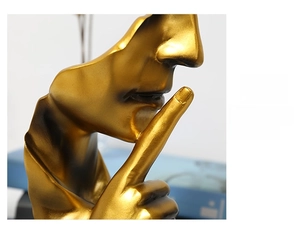 Macro detail of golden resin sculpture showing finger to lips silence gesture texture