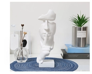 Abstract white resin face sculpture for home decor on a blue mat with modern books