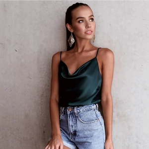 Detail of dark green satin camisole featuring delicate straps and a stylish cowl neckline