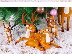 Detailed view of lifelike reindeer figurines set on snow with festive Christmas tree background