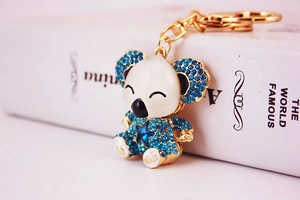Close-up of cute koala keychain with blue rhinestones and gold ring on book background