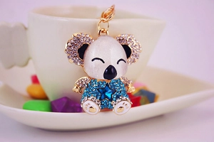Close-up of golden koala keychain with white pearlescent body and blue rhinestones